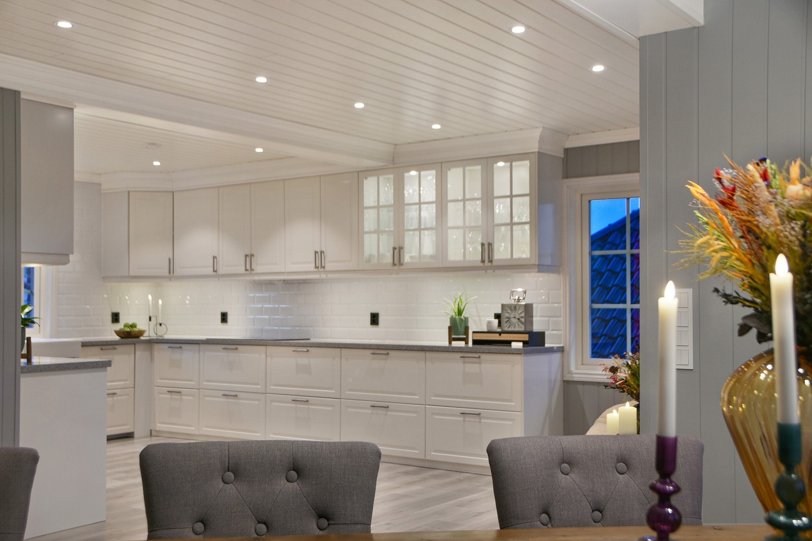 Stort kjøkken med hvite profilerte fronter og benkeplater i polert stein. Galleribilde