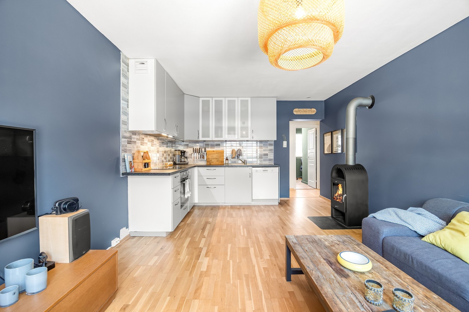 Stuen ligger i en åpen løsning mot kjøkkenet. Stuen har trestavs parkett, blåmalte veggflater. Galleribilde