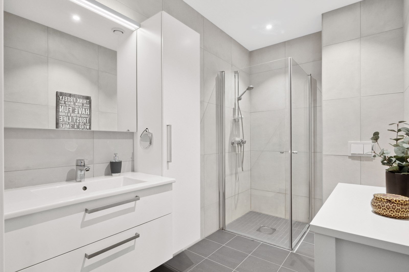 Badet er oppgradert utover standardleveranse og har flislagte overflater som gir en god atmosfære. Veggene er kledd med store, kalkfargede flis i fin kombinasjon med mørkegrå fliser over gulvvarme. Galleribilde