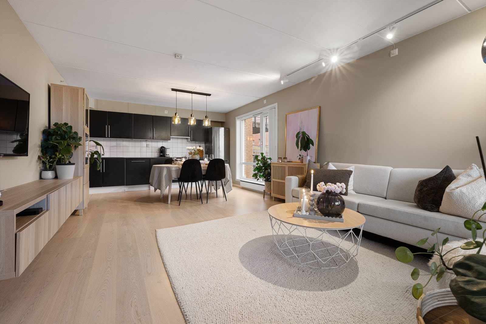 Boligen har en åpen og innbydende stue- og kjøkkenløsning som skaper en sosial og romslig atmosfære Galleribilde