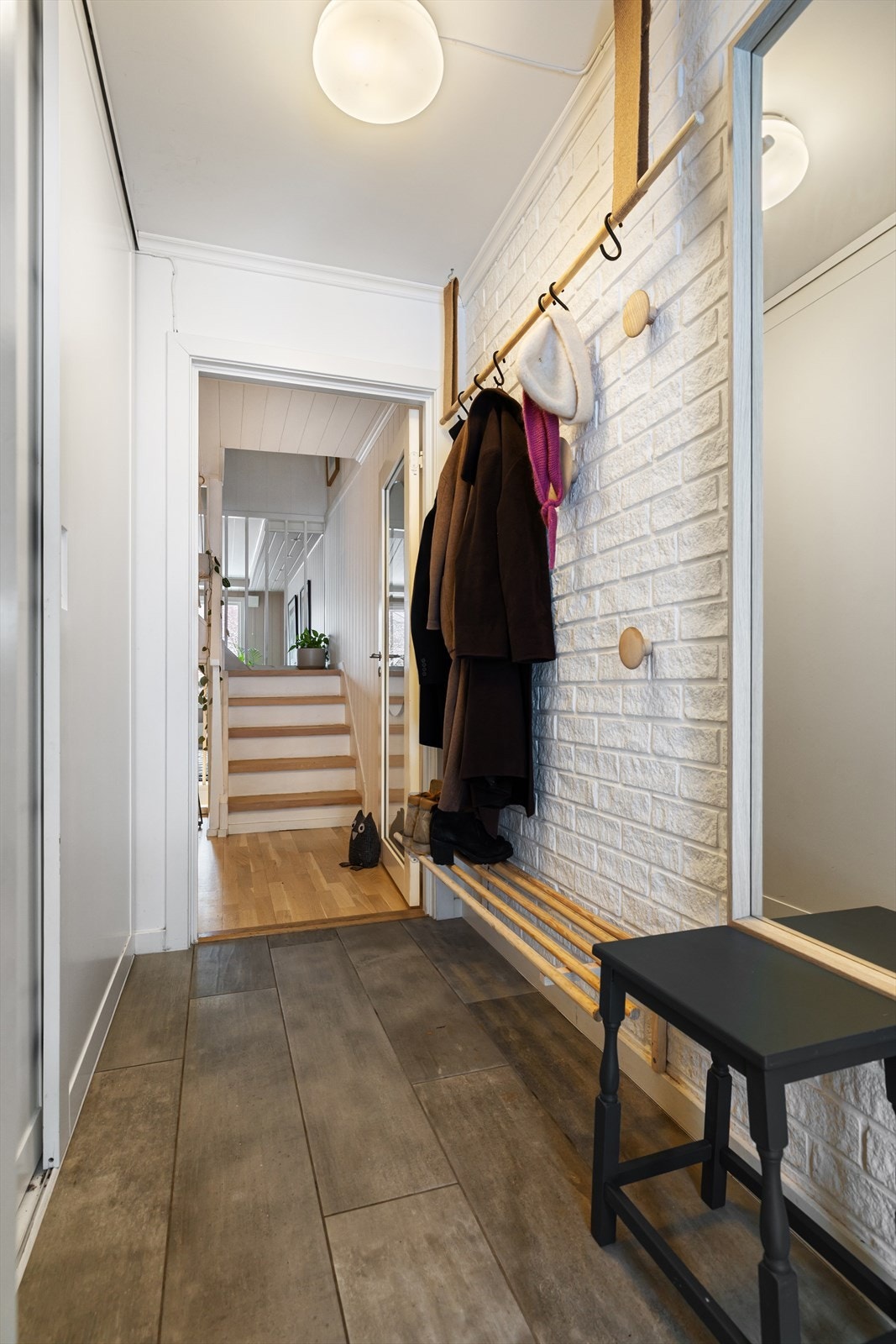 Innbydende entré med plass til ytterklær og sko i plassbygd skyvedørsgarderobe. Gulv med fliser og varmekabler. Galleribilde