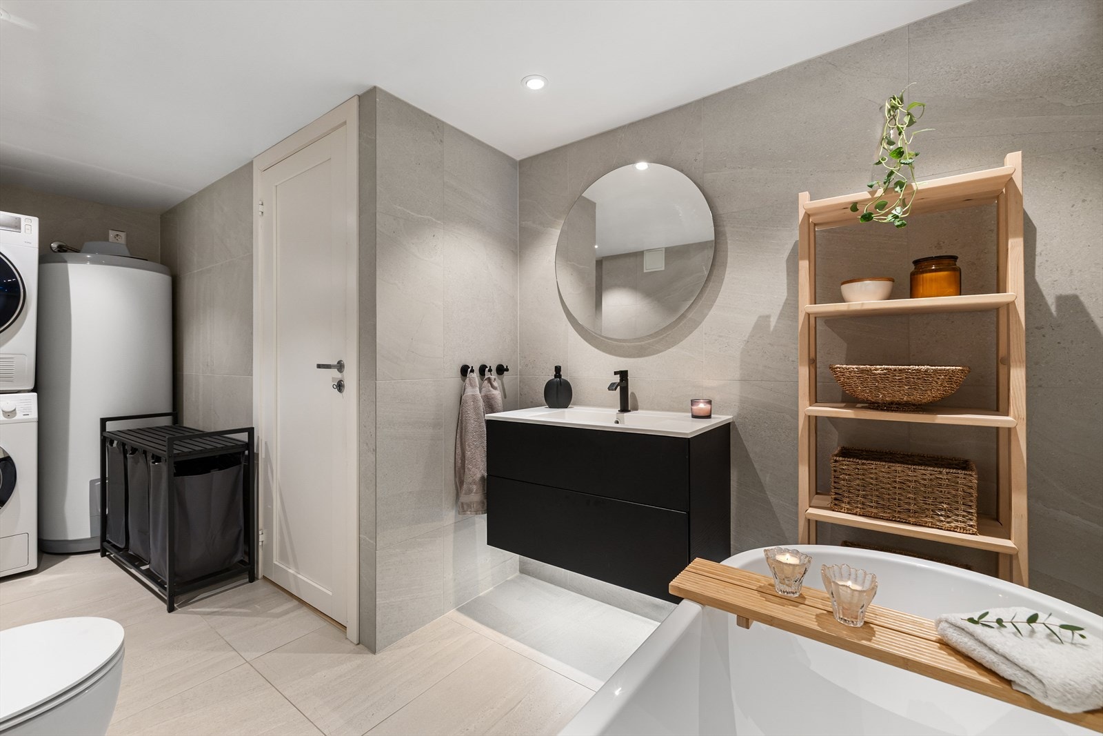 Badet er innredet med vegghengt klosett, baderomsinnredning med heldekkende servant, speil, badekar, vaskemaskin og tørketrommel. Galleribilde