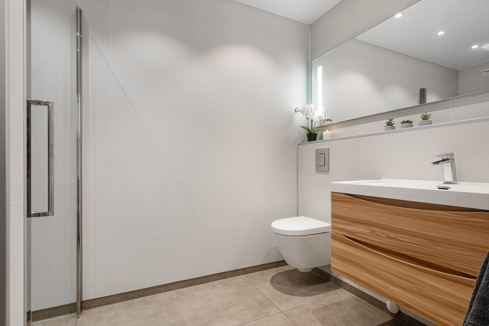 Innredningen består av vegghengt toalett, helservant på skuffeseksjon, speil med belysning og dusjnisje. Galleribilde