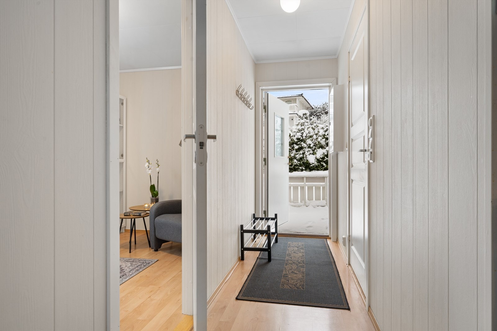 Velkommen inn! Lysmalt entré med laminat på gulv. Det er montert knaggrekke. Galleribilde