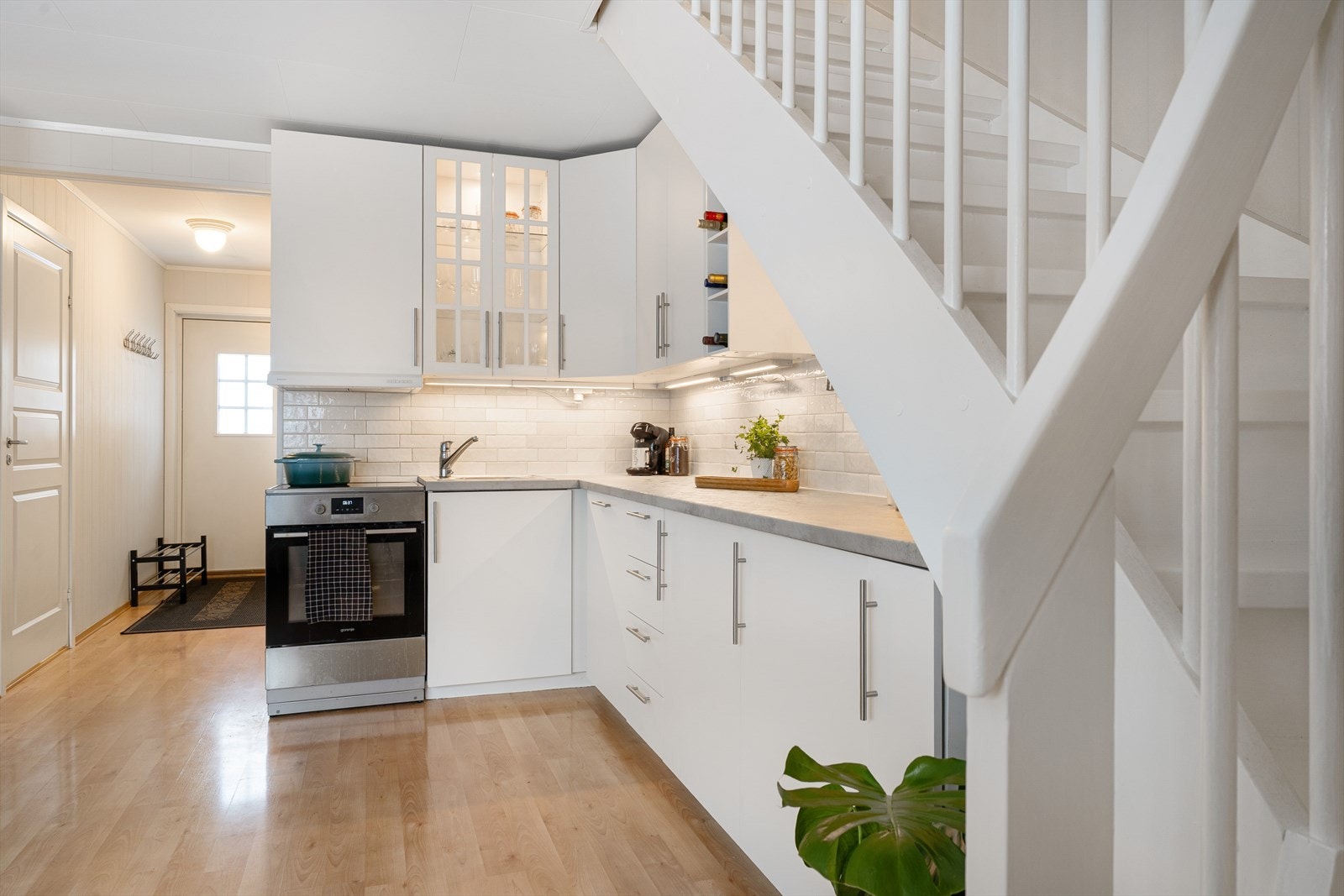 Tidløs kjøkkeninnredning med hvite, slette fronter, vitrineskap og laminat benkeplate. Galleribilde