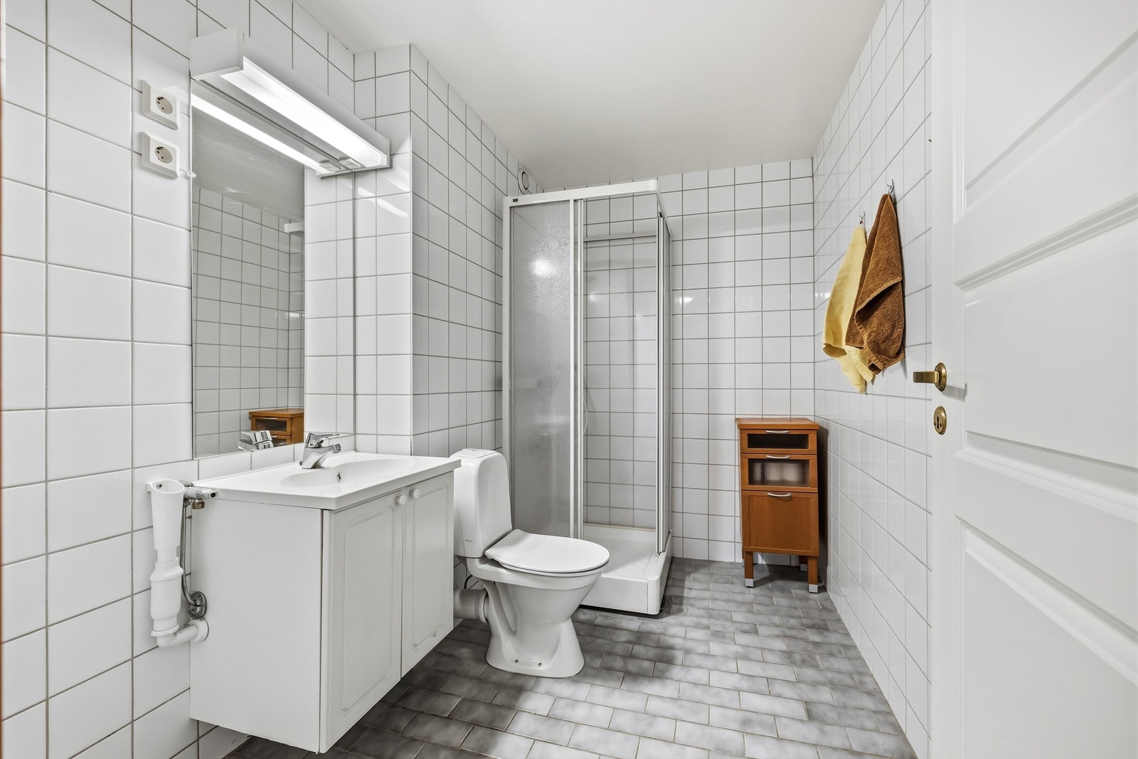 Badet er helfliset og innredet med servantmøbel, toalett og dusjkabinett. Opplegg til vaskemaskin Galleribilde