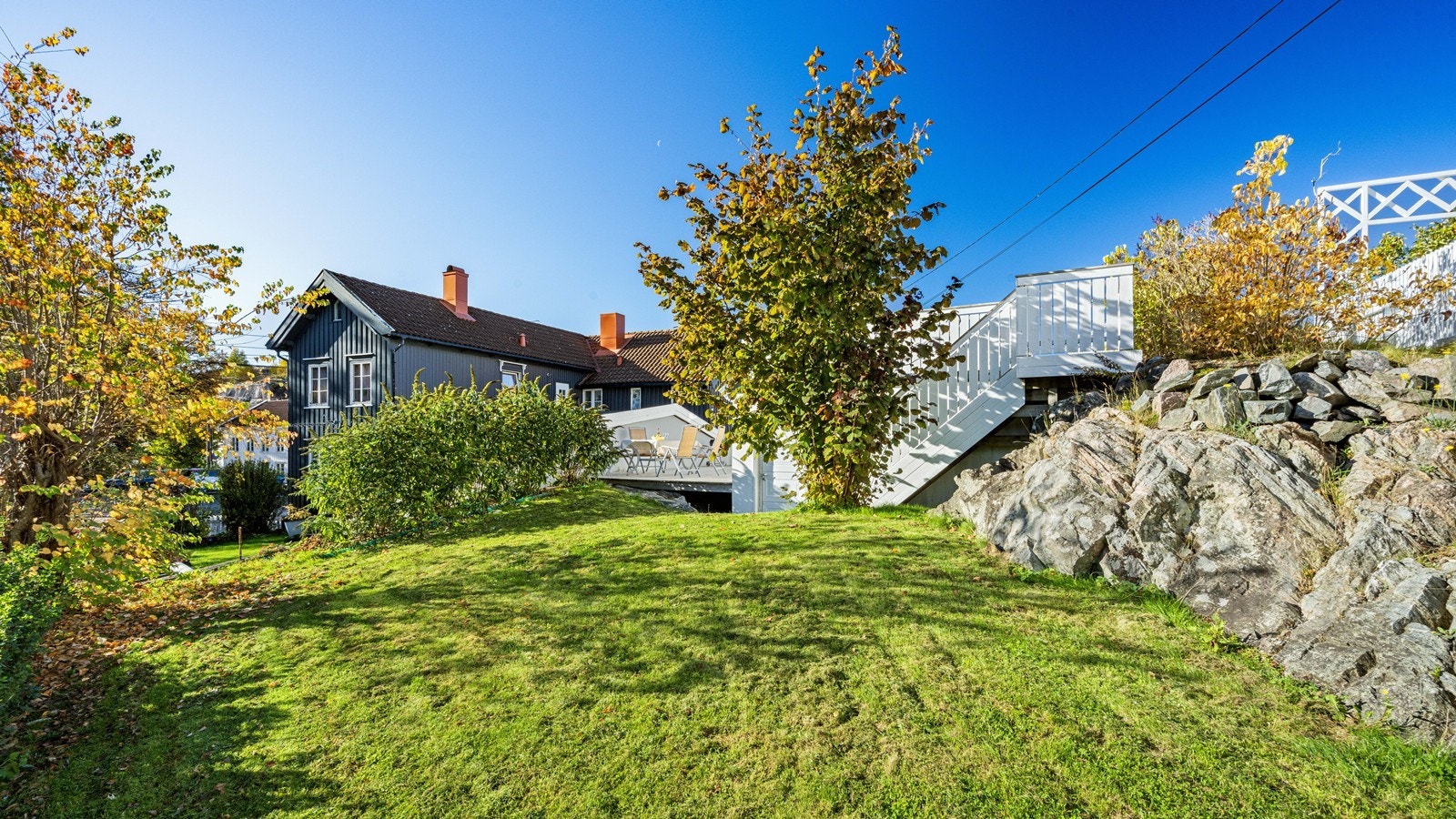Romslig hage med stor gressplen bak garasjen Galleribilde