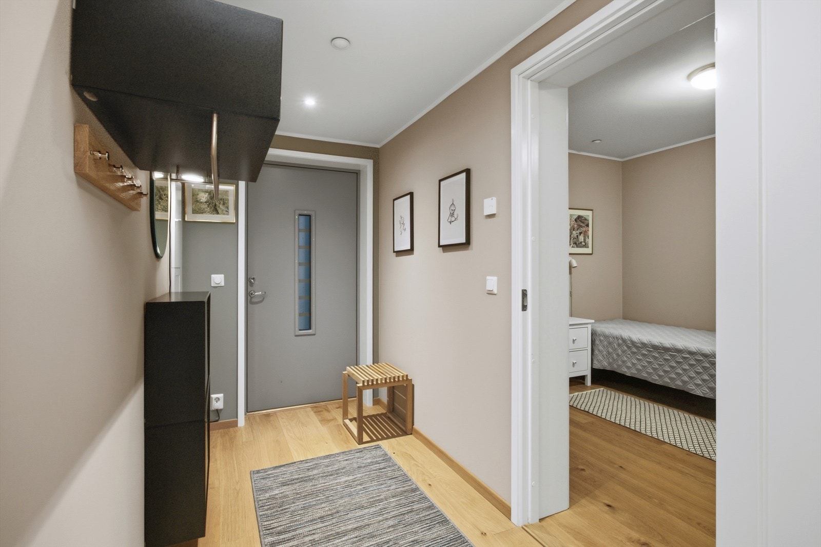 Fra den kombinerte entrèen og gangen er det dør m/sidefelt av glass som fører deg videre inn i leiligheten. Rommet oppleves som lyst, bredt og innbydende. Innerst i rommet er det en praktisk skyvedørsgarderobe med innredning og takhøye speildører. Galleribilde