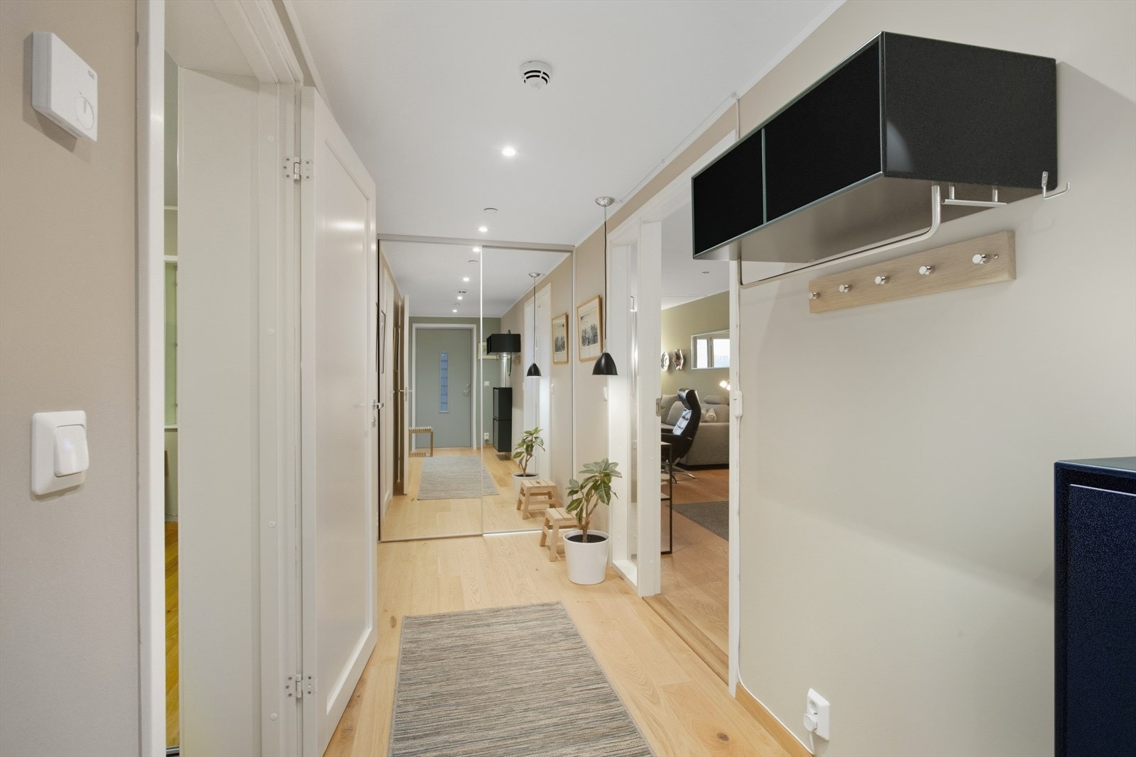 De innfelte downlightsene i himlingen med nivåjustering gir god belysning. Glassdør med sidefelt leder deg videre inn i leiligheten. Skoskap samt vegghylle (alt fra IN - Interiørbutikken) i entre/gang medfølger. Galleribilde