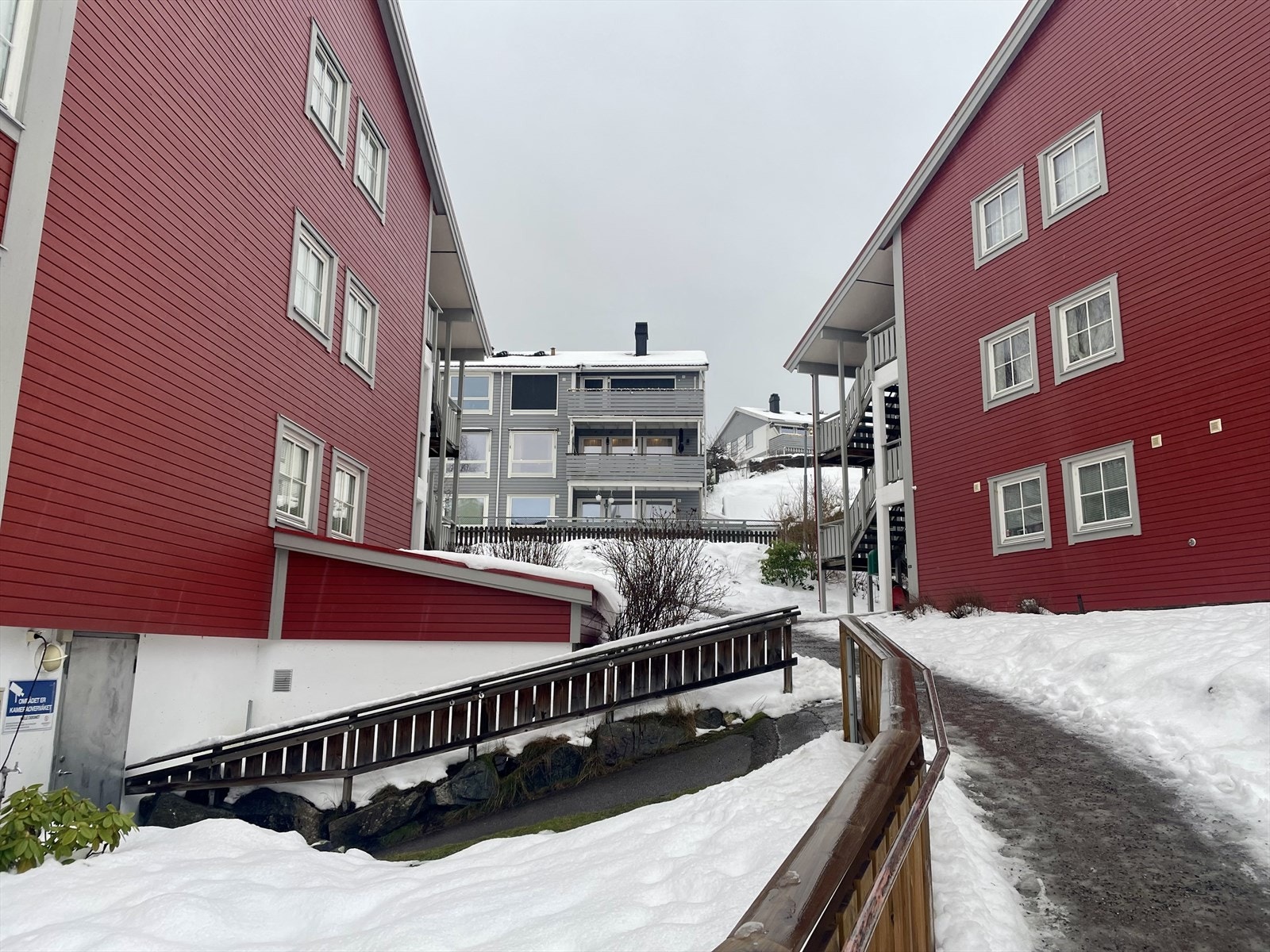 Det er adkomst fra bolig i bygget til høyre og ned til grå dør inn til garasjeplass Galleribilde