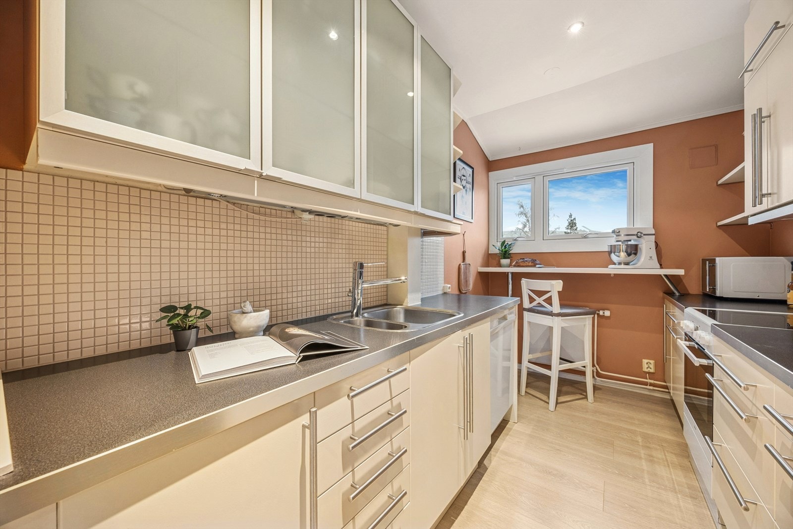 Kjøkkenet er innredet med slette fronter og laminat benkeplate. Det flislagte partiet over benken gjør det enkelt å holde arealet rent. Galleribilde