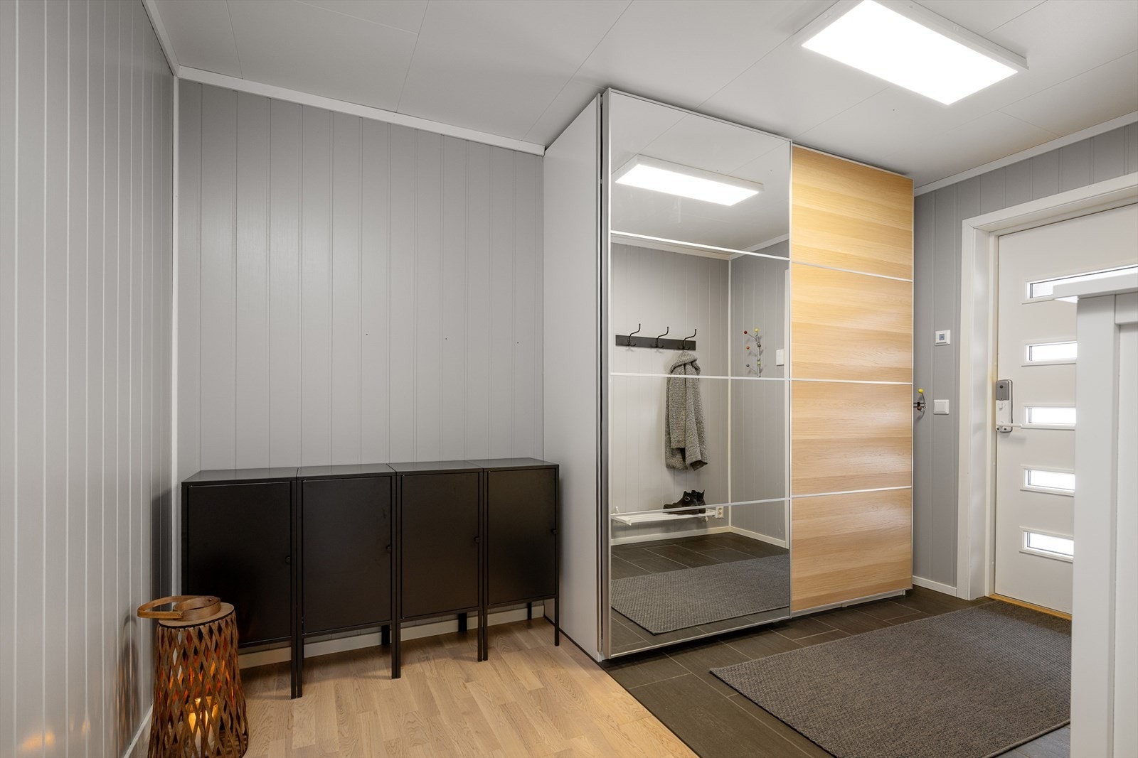 Romslig entré med flislagt gulv og en stor skyvedørsgarderobe med speilfronter. Galleribilde