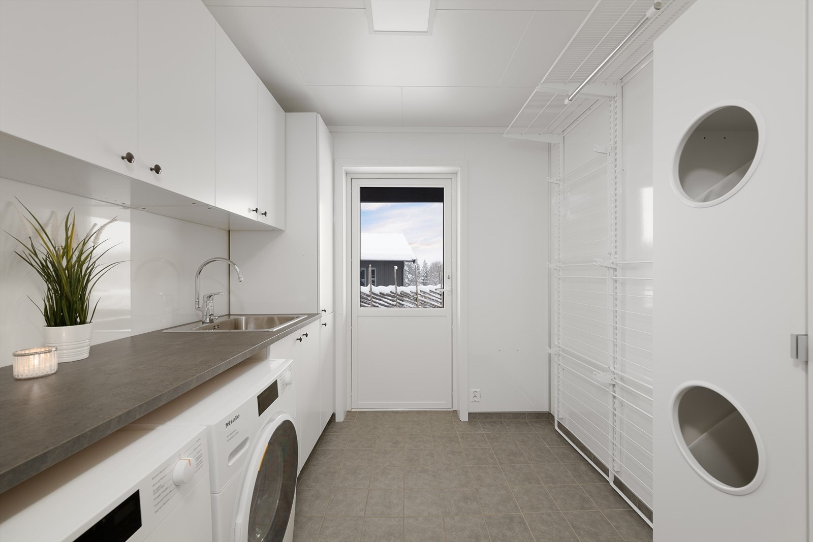 Separat og romslig vaskerom med egen utgang, rikelig med skapplass og opplegg for vaskemaskin. Smarte og praktiske detaljer og løsninger. Galleribilde
