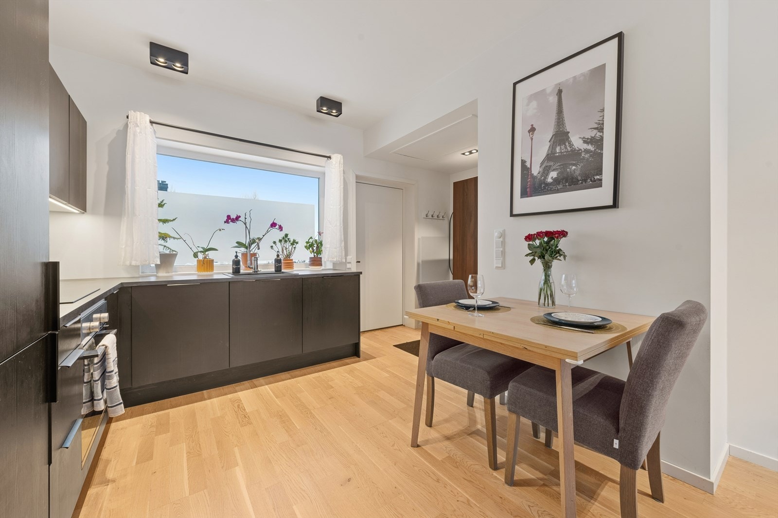 Kjøkkenet har en moderne og funksjonell utforming med innredning fra 2021, levert med mørke, glatte laminerte fronter og grå laminerte benkeplater. Galleribilde