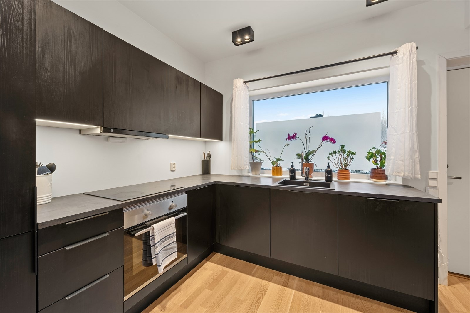 Kjøkkenet har innredning med mørke glatte fronter og grå benkeplater. Galleribilde