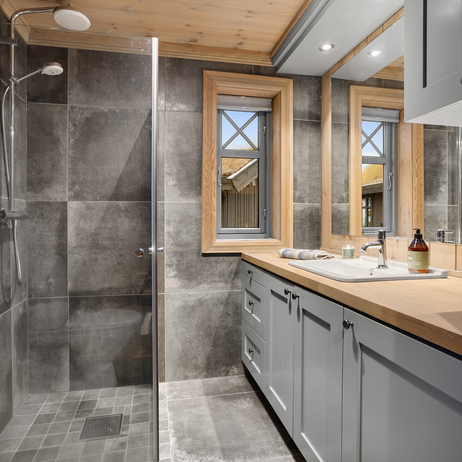 Flislagt baderom i stabburet, med toalett, dusjnisje og innredning med servant Galleribilde