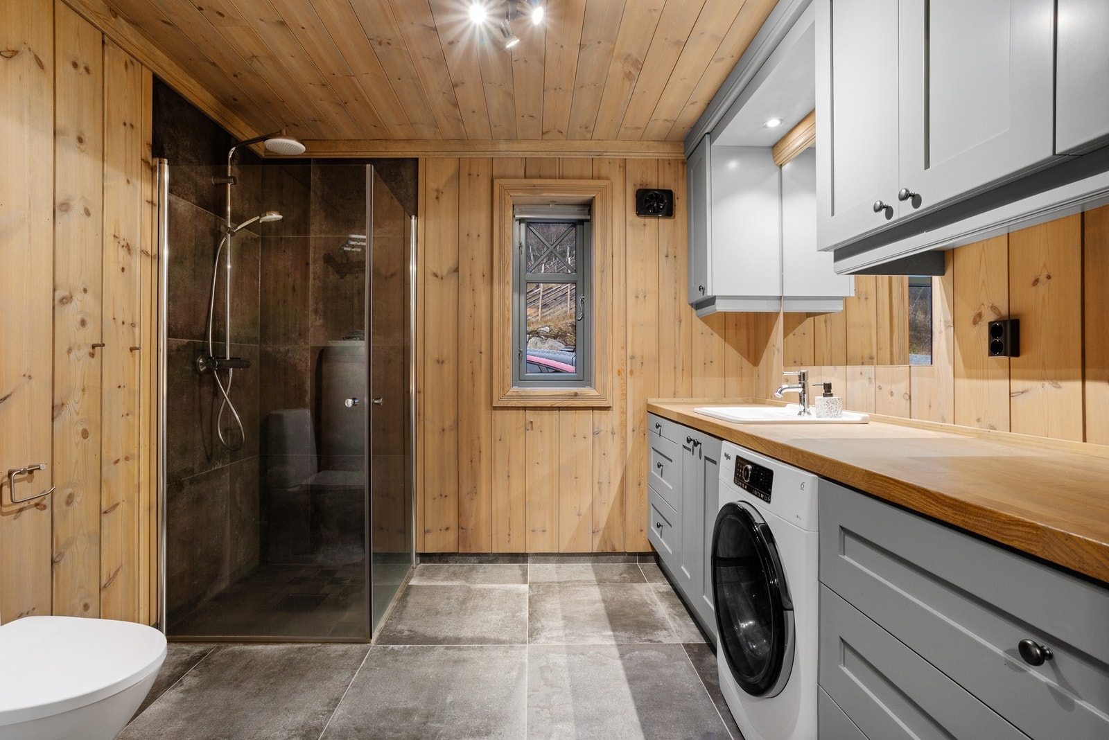 Baderom med toalett, dusjnisje og innredning med servant. I tillegg opplegg til vaskemaskin og god benkeplass. Galleribilde