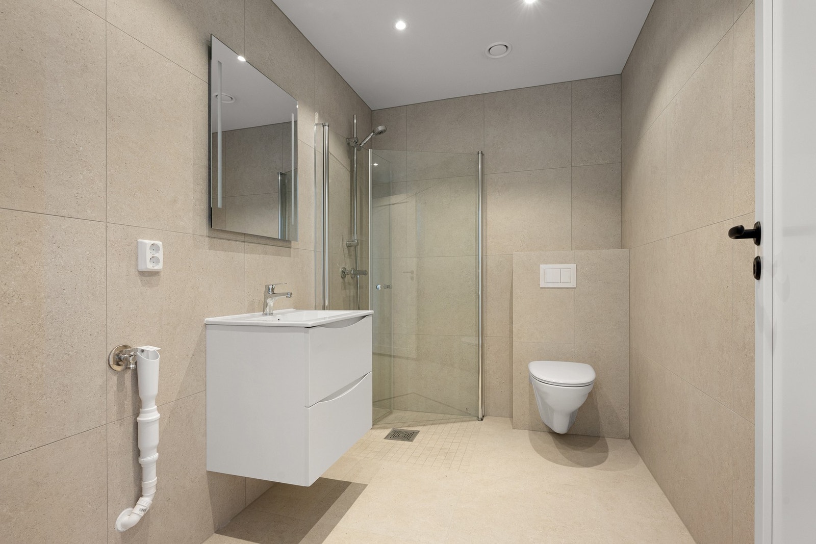 Delikat bad med store, stilrene fliser, behagelig gulvvarme og dusjhjørne i glass. Galleribilde