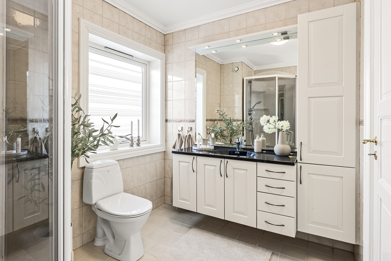 Baderomsinnredning med malte, profilerte fronter og benkeplate i stein. Varmekabler i gulvet. Galleribilde