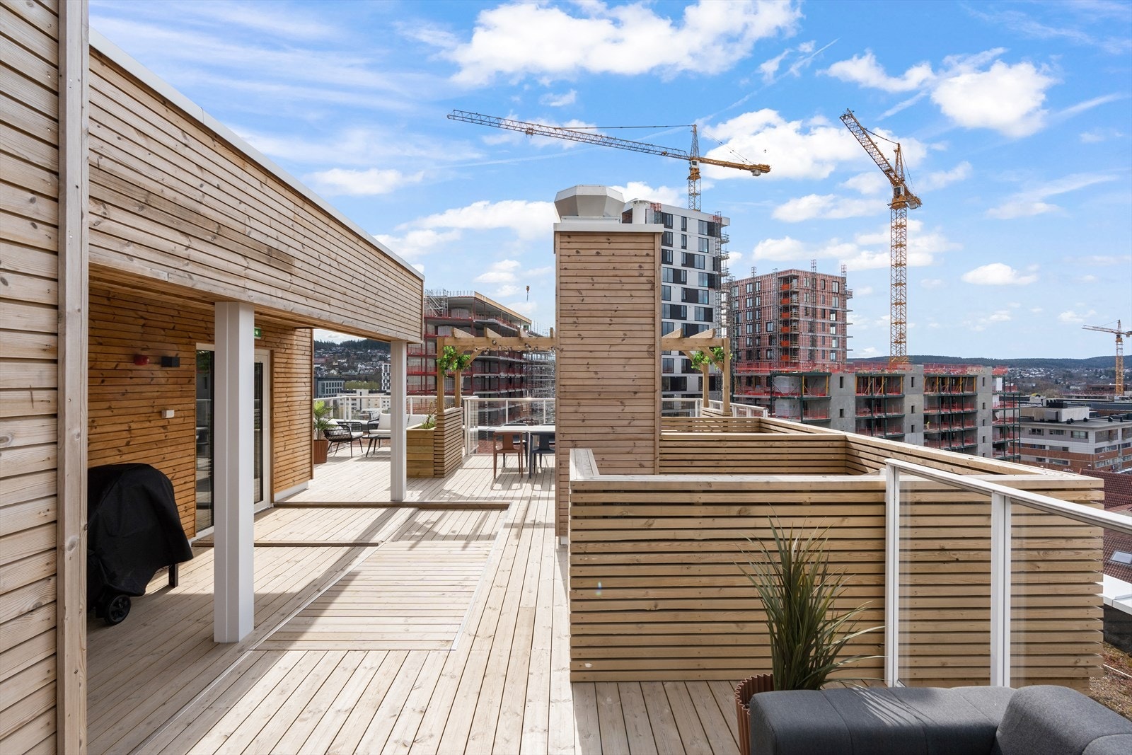Takterrassen har dekke i tre, plassbygde blomsterkasser, pergola og moderne sittegrupper. Galleribilde