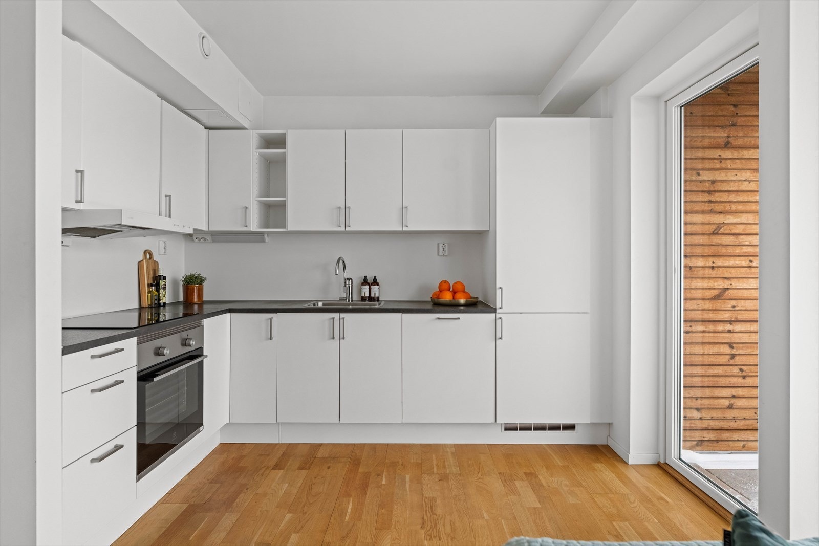 Kjøkkenet har en pratisk innredning med rene linjer. Innredningen har hvite fronter, mørke laminatbenkeplater, oppvaskkum og integrerte hvitevarer. Galleribilde