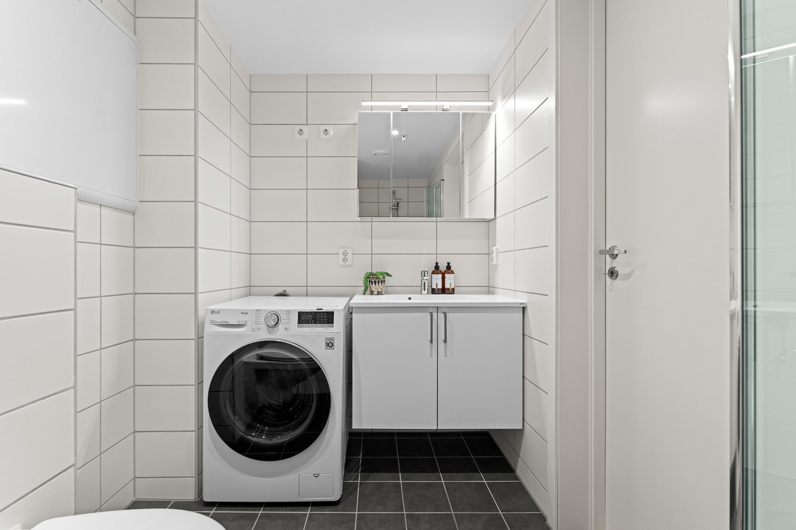 Badet har skapinnredning med heldekkende servant, samt dobbelt speilskap med belysning. Ved siden av innredningen er det opplegg for vaskemaskin og tørketrommel i søyleløsning. Galleribilde