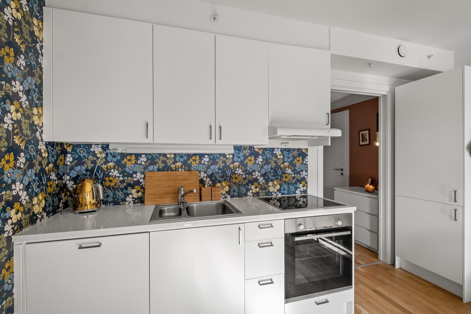 Kjøkkeninnredningen har hvite, slette fronter, laminat benkeplate og integrerte hvitevarer. Galleribilde