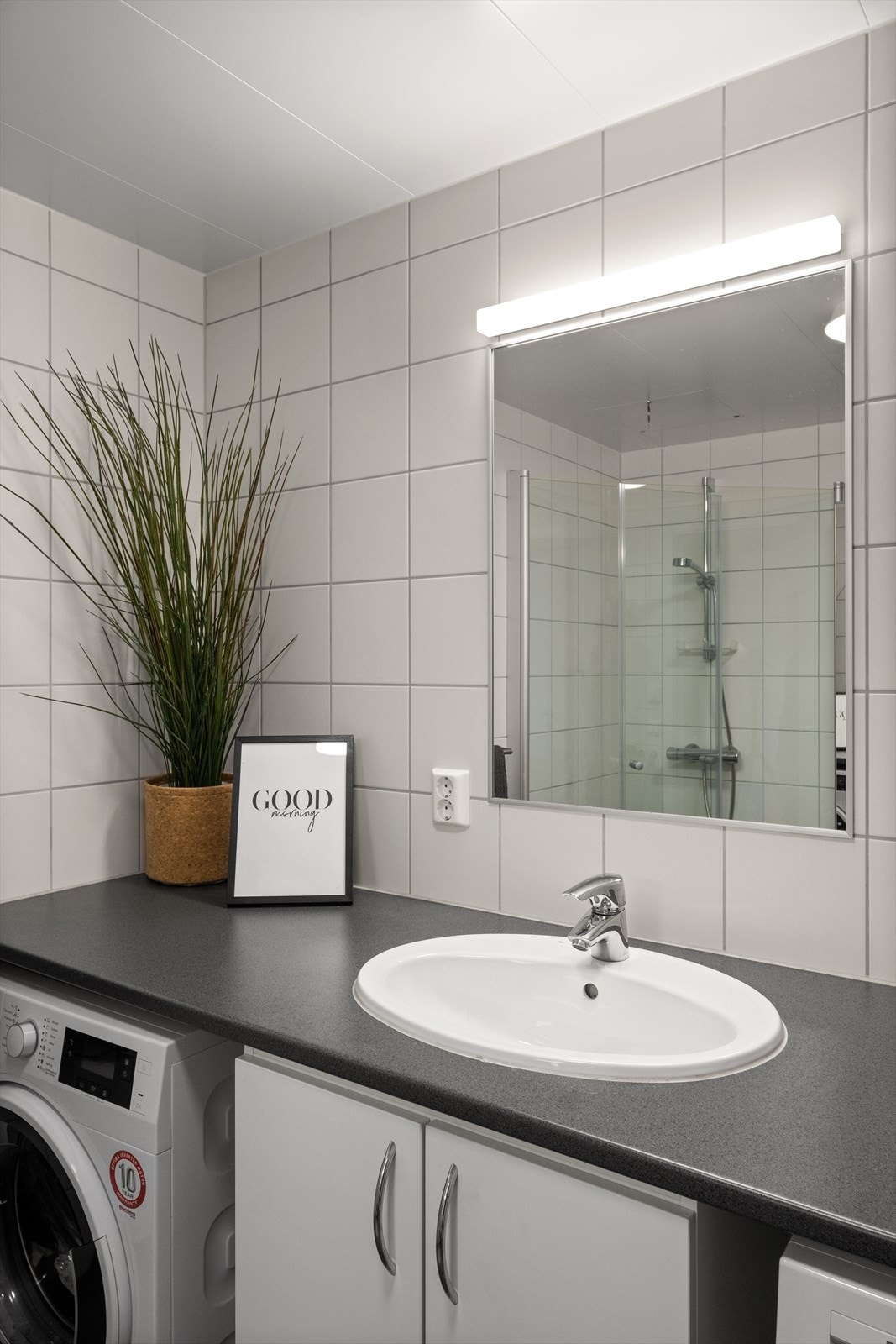 Badet er innredet med servant på skapseksjon, dusjhjørne, vegghengt toalett og opplegg for vask/tørk. Galleribilde