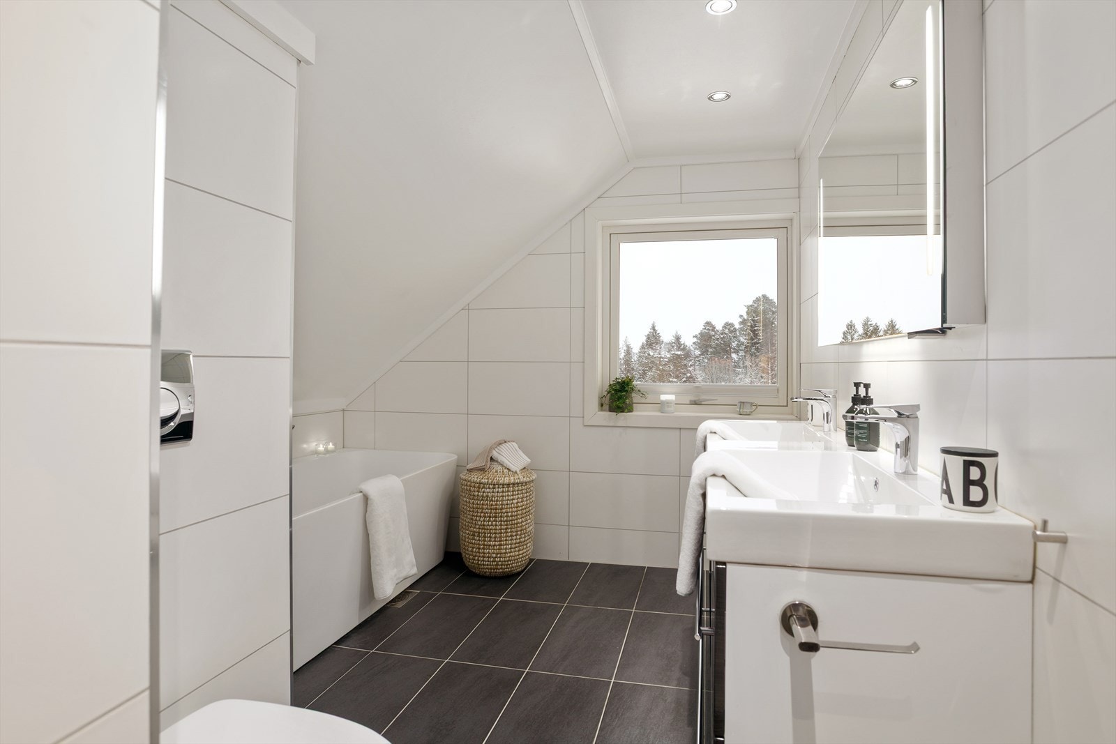 Badet er innredet med servantskap med dobbel servant, speil med innebygd belysning, vegghengt toalett med innebygd sisterne, dusjnisje med glass-skyvedør samt frittstående badekar. Galleribilde