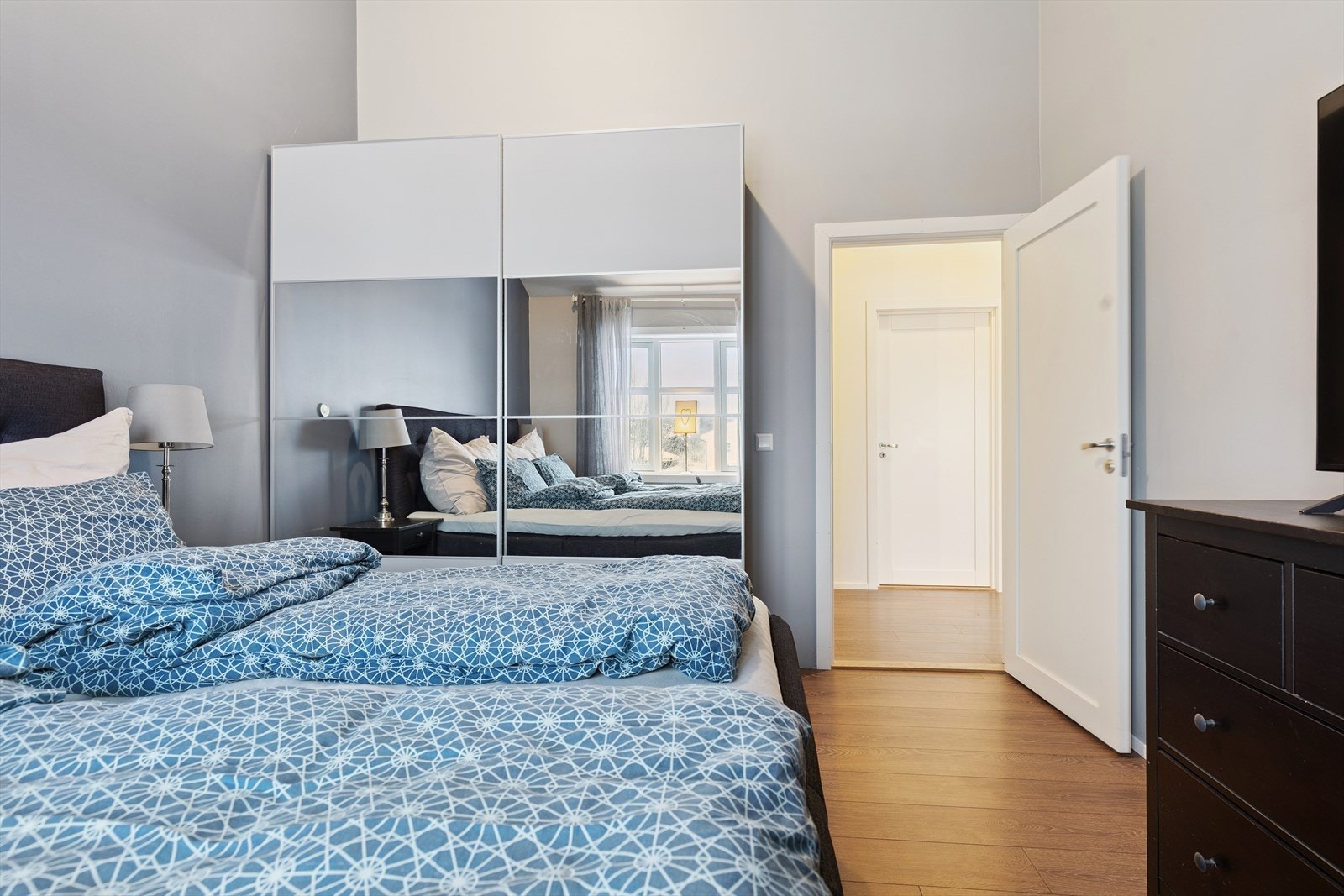 En stor skyvedørsgarderobe med speilfronter gir rikelig med oppbevaringsplass. Galleribilde