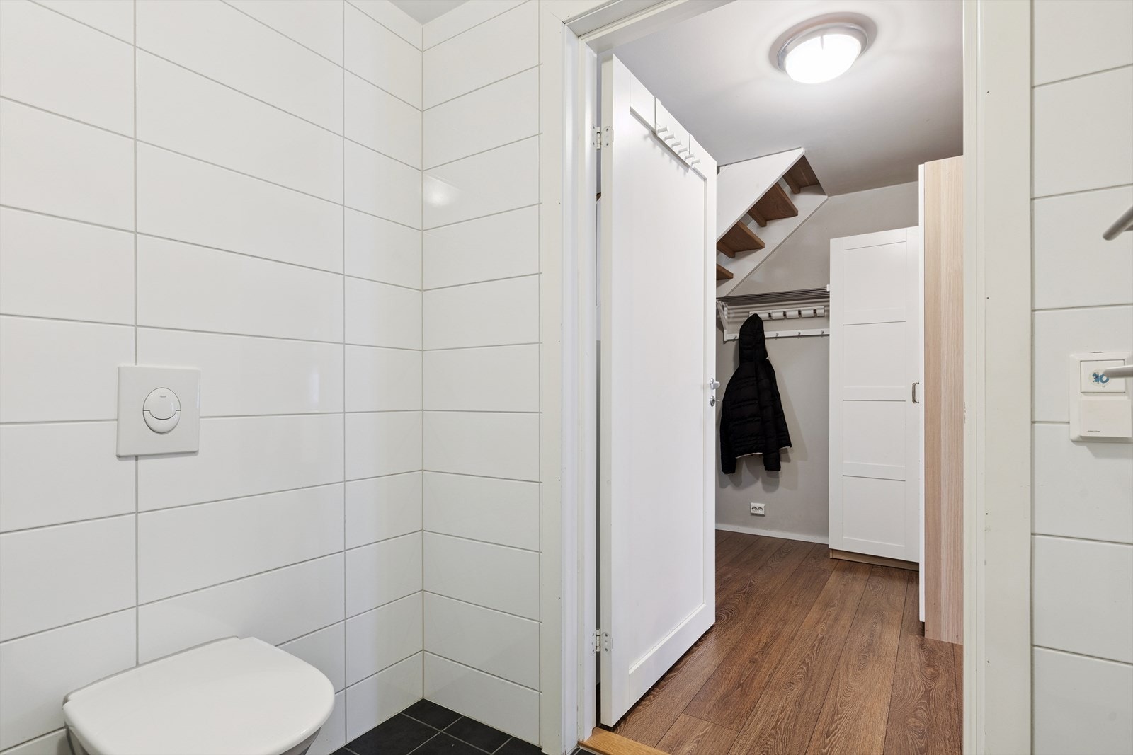 Praktisk bad i første etasje, tilknyttet entréen. Badet er helfliset med mørke gulvfliser og hvite veggfliser. Galleribilde