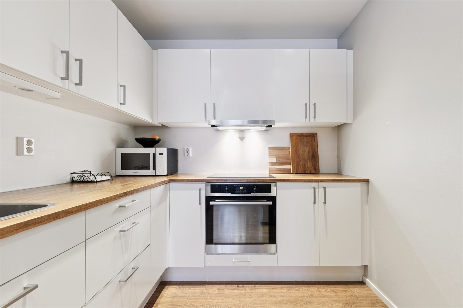 Innredningen har glatte, hvite fronter og integrert stekeovn med platetopp. Galleribilde