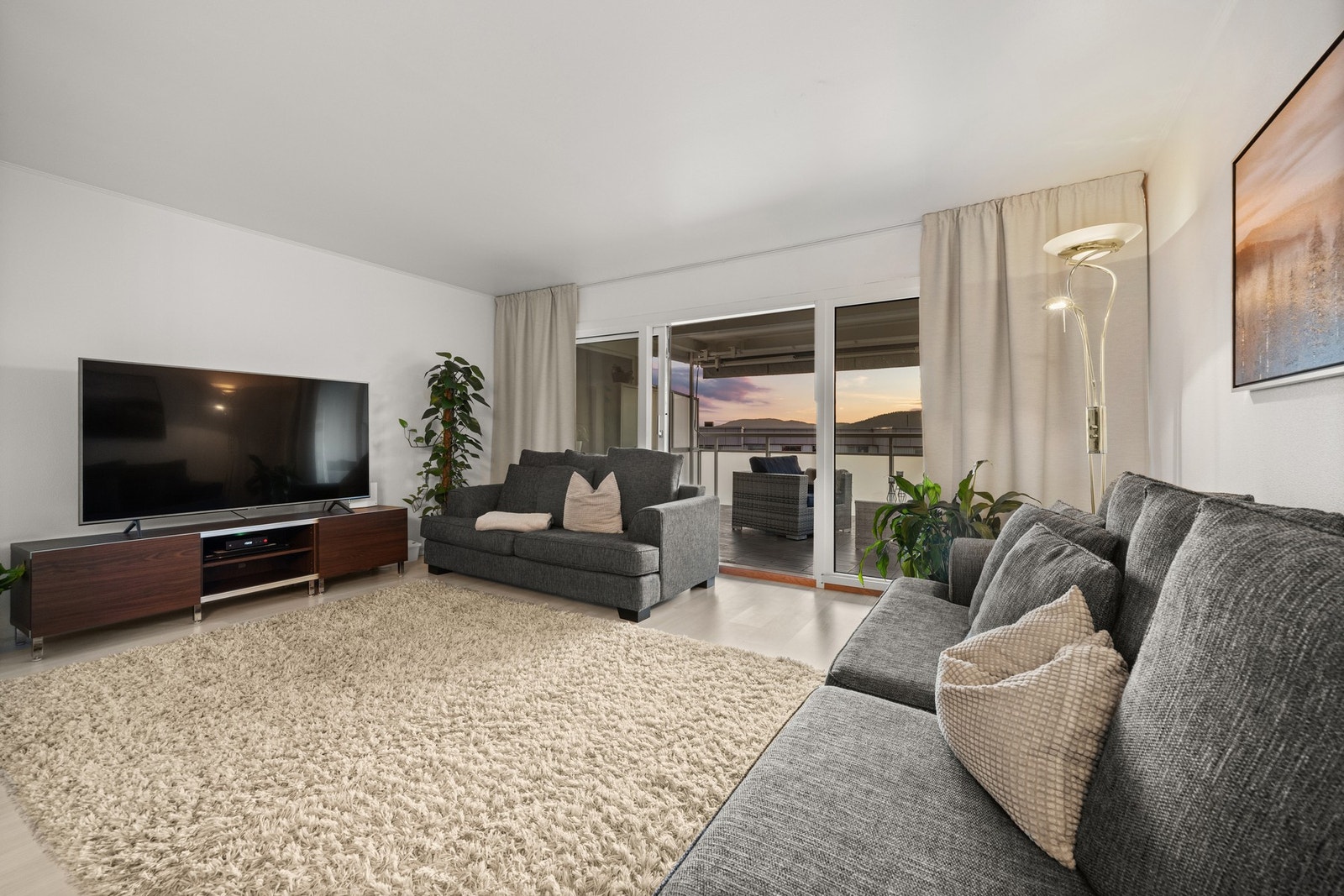 Stuens store vindusflater gir rikelig med naturlig lysinnslipp inn i leilighetens sosiale sone Galleribilde