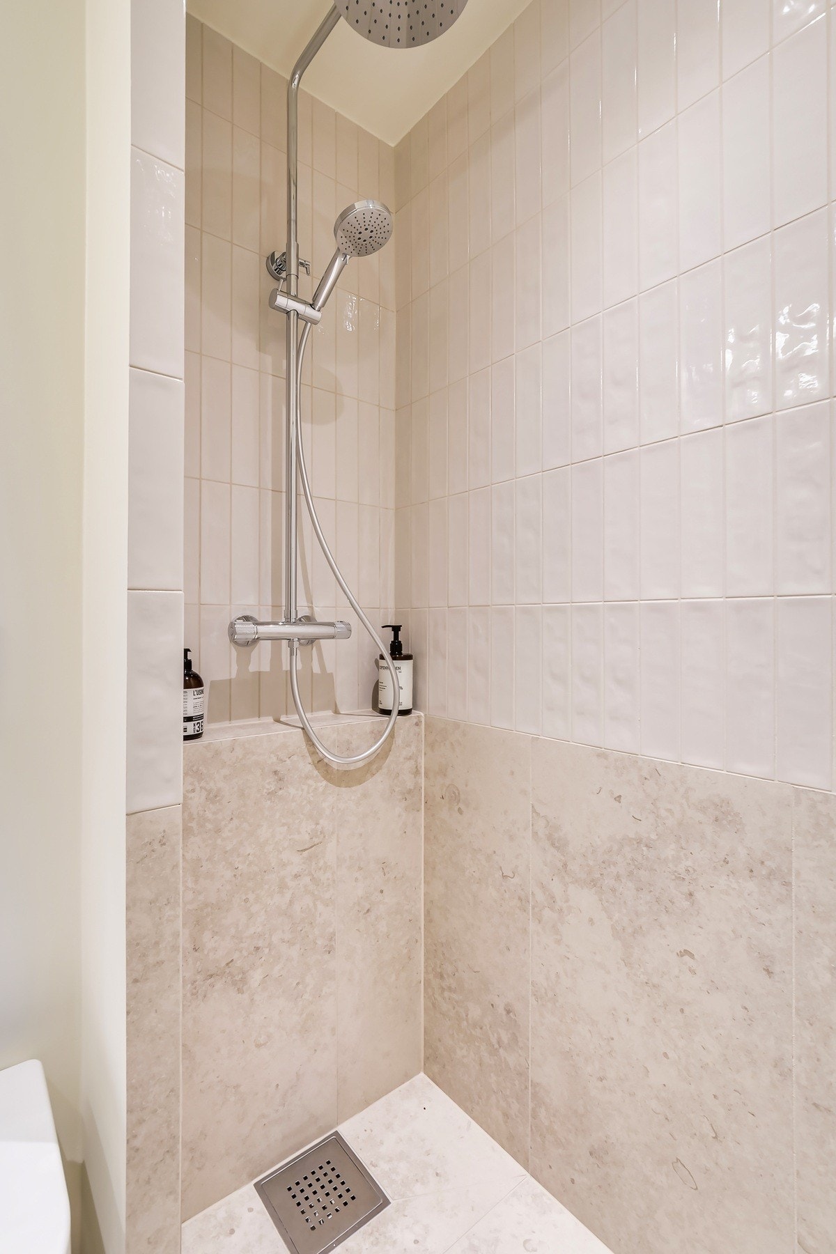 Dusjsonen er utstyrt med innfellbar glassdør og vegghengt dusjarmatur med både regnfallsdusj og hånddusj - en elegant og funksjonell løsning. Galleribilde