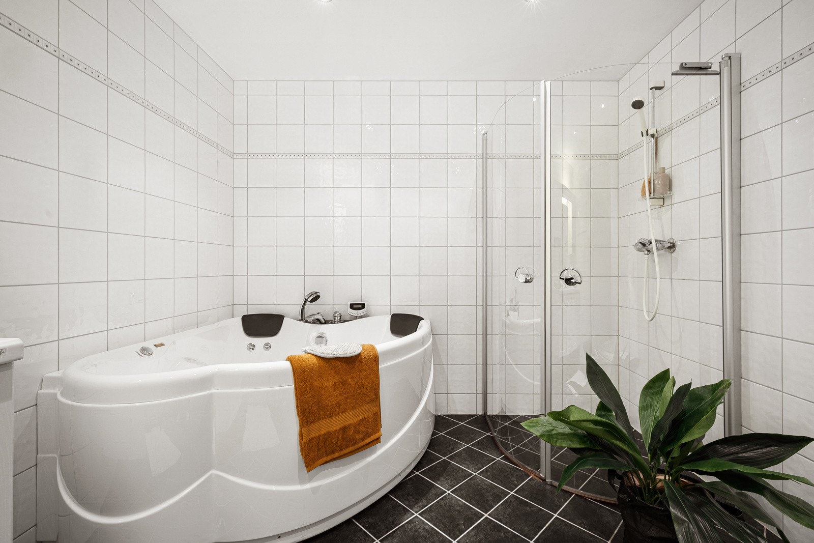 Rommet har innredning med nedfelt servant, veggmontert toalett, badekar og dusjvegger/hjørne. Galleribilde