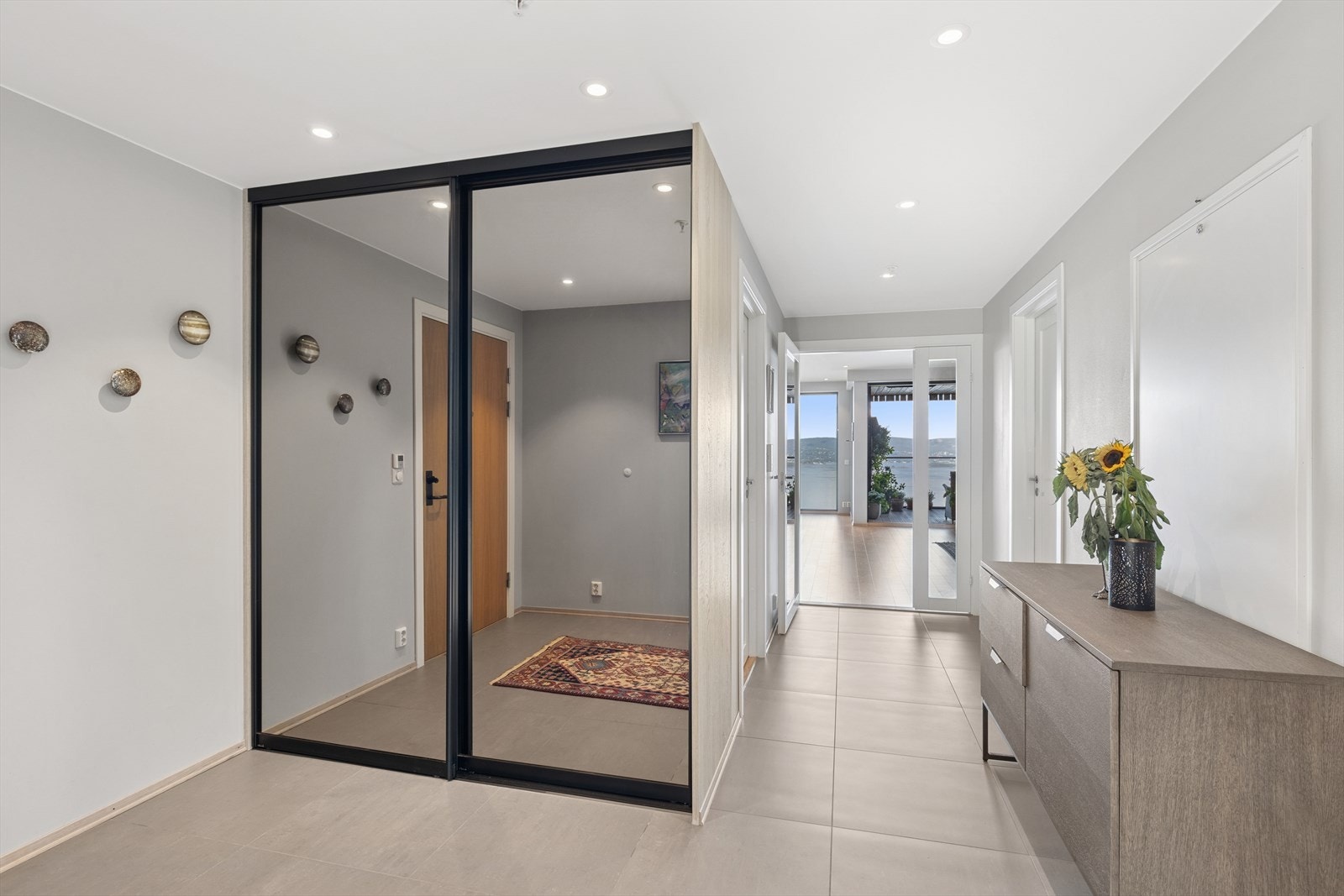 Flislagt gang med skyvedørsgarderobe og spotter i tak - både praktisk og elegant. Galleribilde