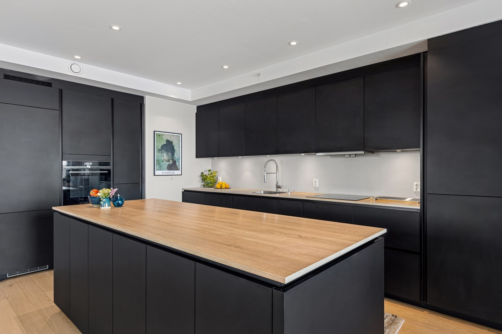 Integrerte hvitevarer og delikat innredning i mørke fargetoner. Galleribilde