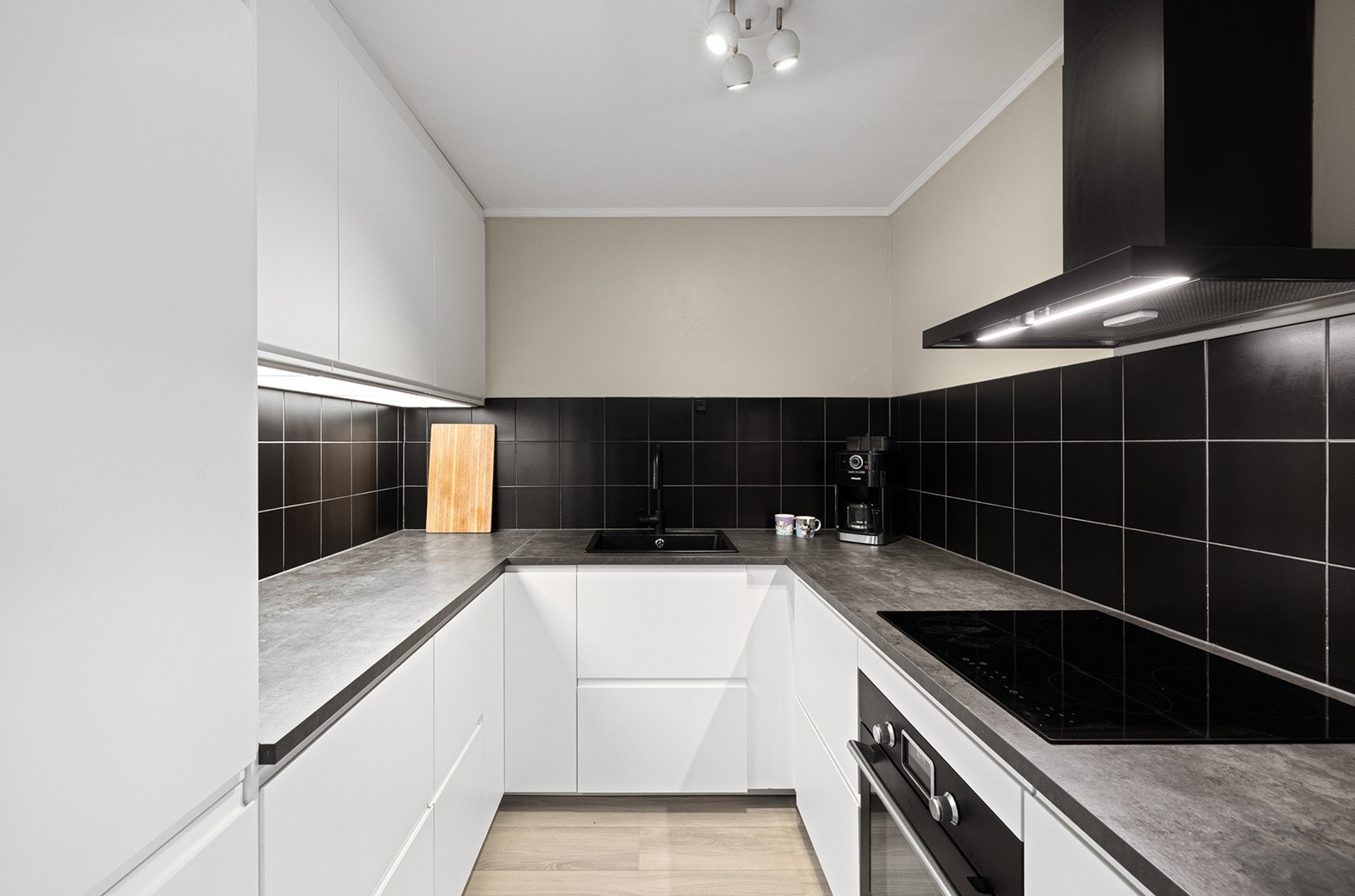 Den mørke flisen gir en elegant kontrast til de hvite, glatte frontene og de lyse overflatene. Galleribilde