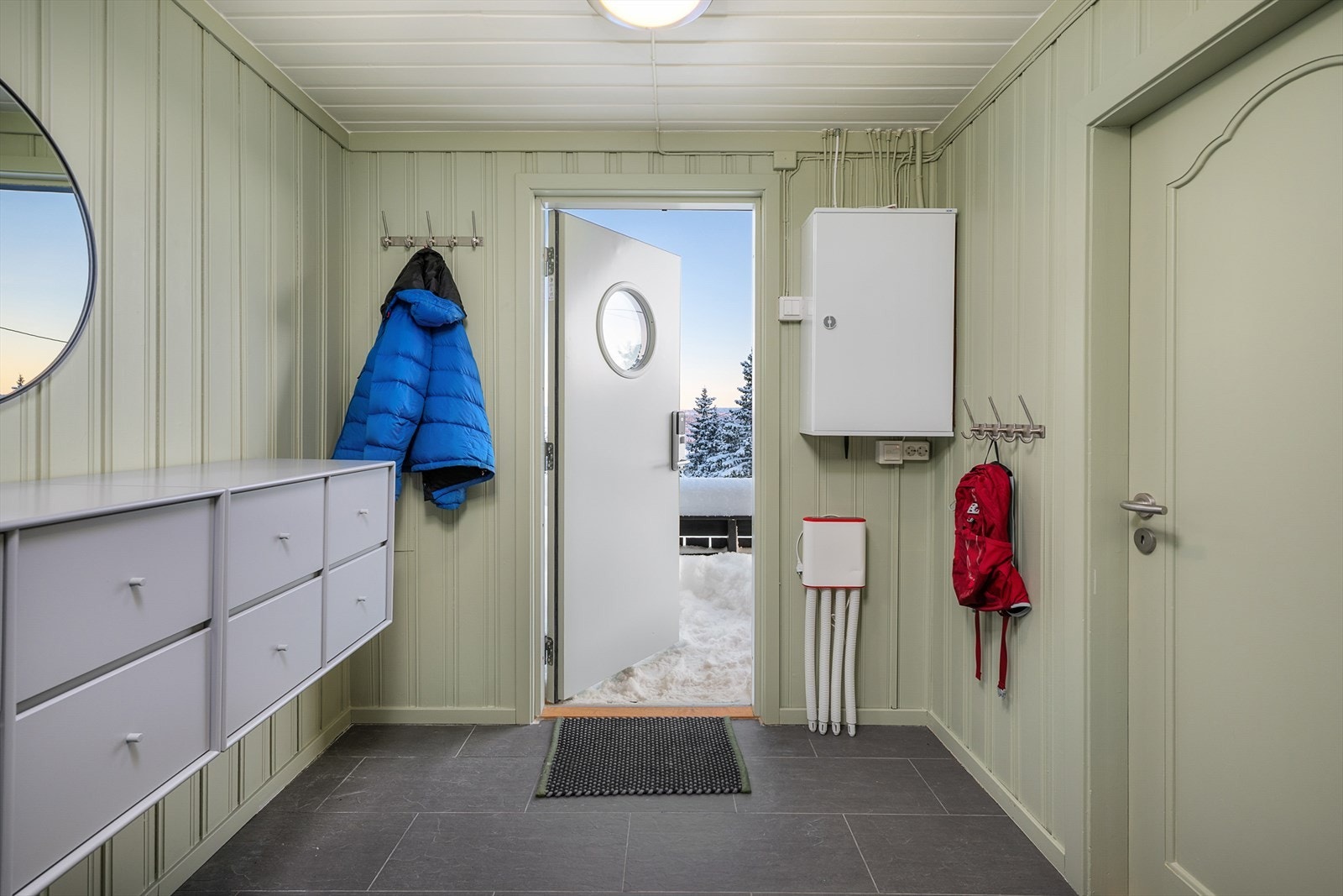 Det er en praktisk entré med flislagt gulv og plass til yttertøy i hytta. Herfra er det adkomst til ett av soverommene. Galleribilde