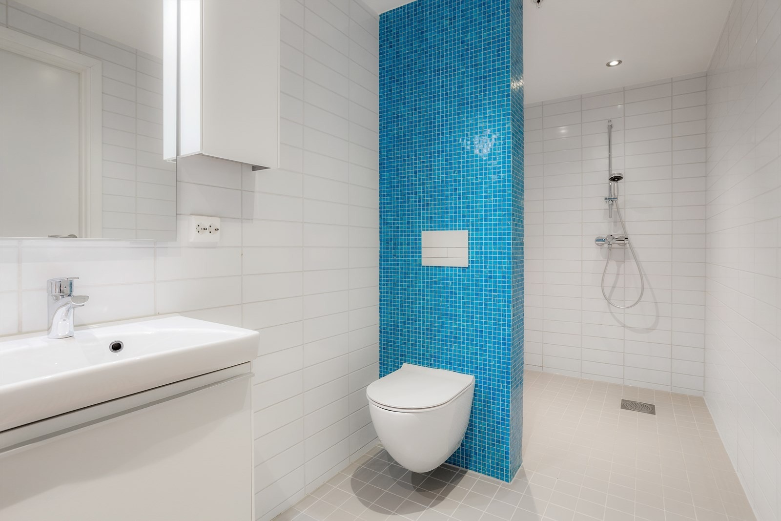 Rommet er innredet med nedfelt servant, veggmontert toalett, dusjhjørne, og opplegg for vaskemaskin Downlights i tak gir god belysning. Galleribilde