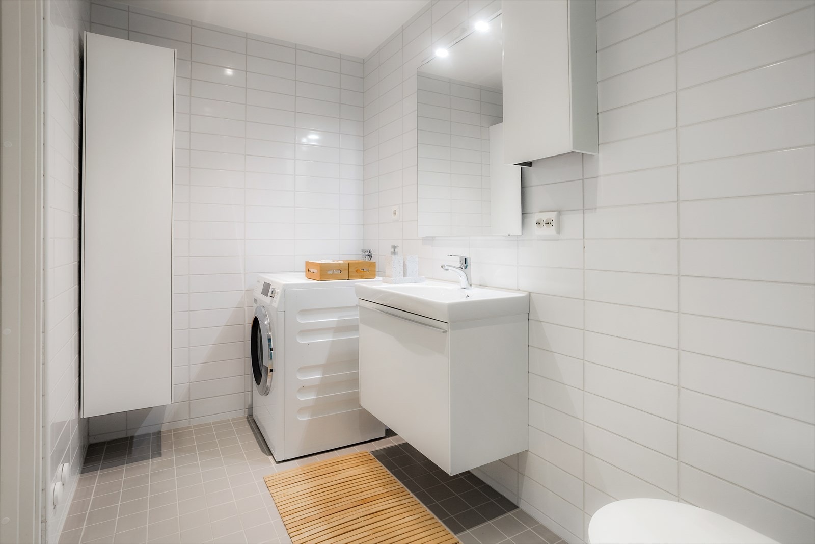 Praktisk og funksjonelt bad med flislagt gulv med varmekabler for ekstra komfort året rundt, flislagte vegger og malt slett tak. Galleribilde