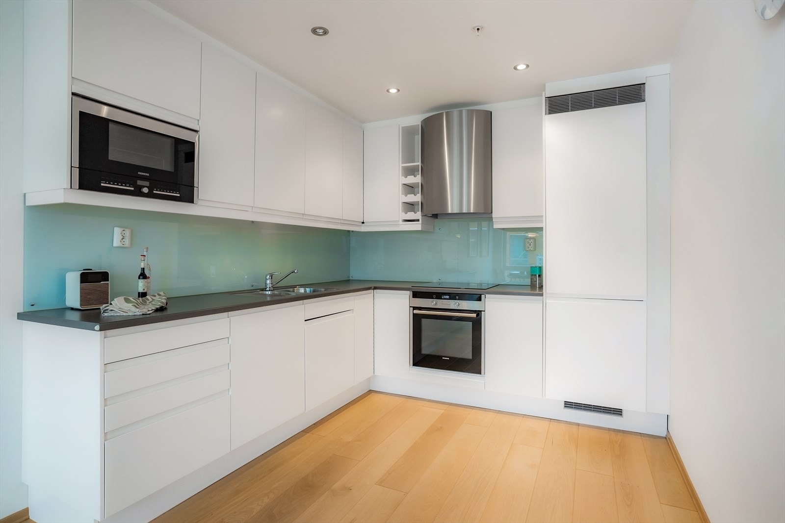 Integrerte hvitevarer bestående av kjøl-/fryseskap, oppvaskmaskin, platetopp, mikroovn og stekeovn. Galleribilde