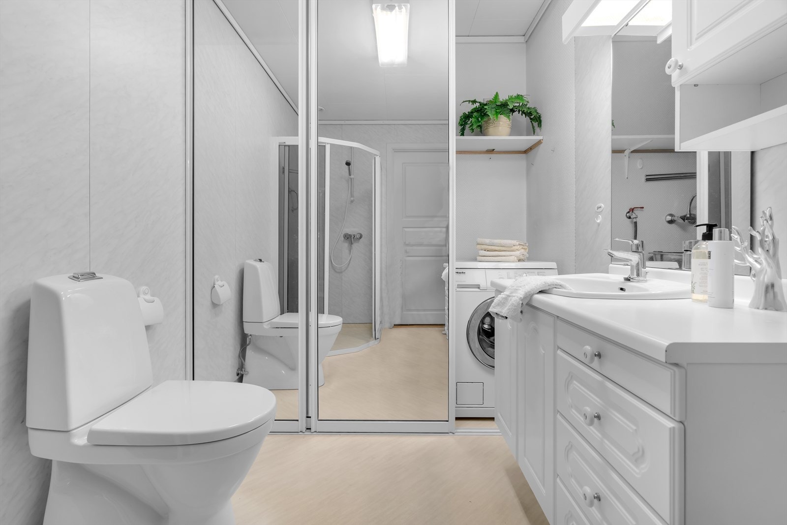 For å skape en ryddig og stilren løsning er vaskemaskinen diskret plassert bak skyvedører. Galleribilde