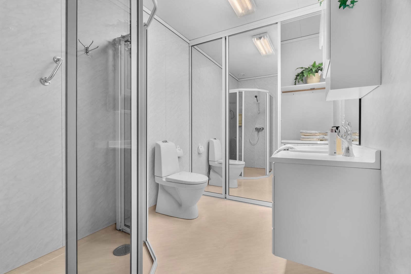 Badet er lyst og funksjonelt, innredet med nedfelt servant, toalett, dusjhjørne og opplegg for vaskemaskin og tørketrommel. Gulvet er belagt med vinylbelegg og har behagelige varmekabler som gir ekstra komfort. Galleribilde