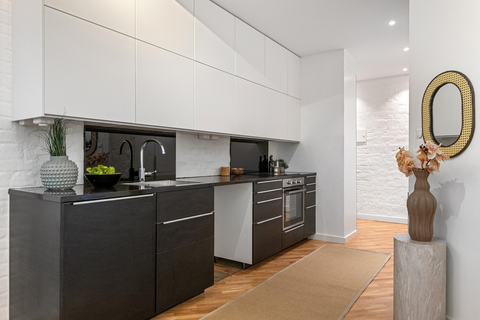 Åpen kjøkkenløsning mot stue med glatte fronter. Benkeplater av stein. Galleribilde