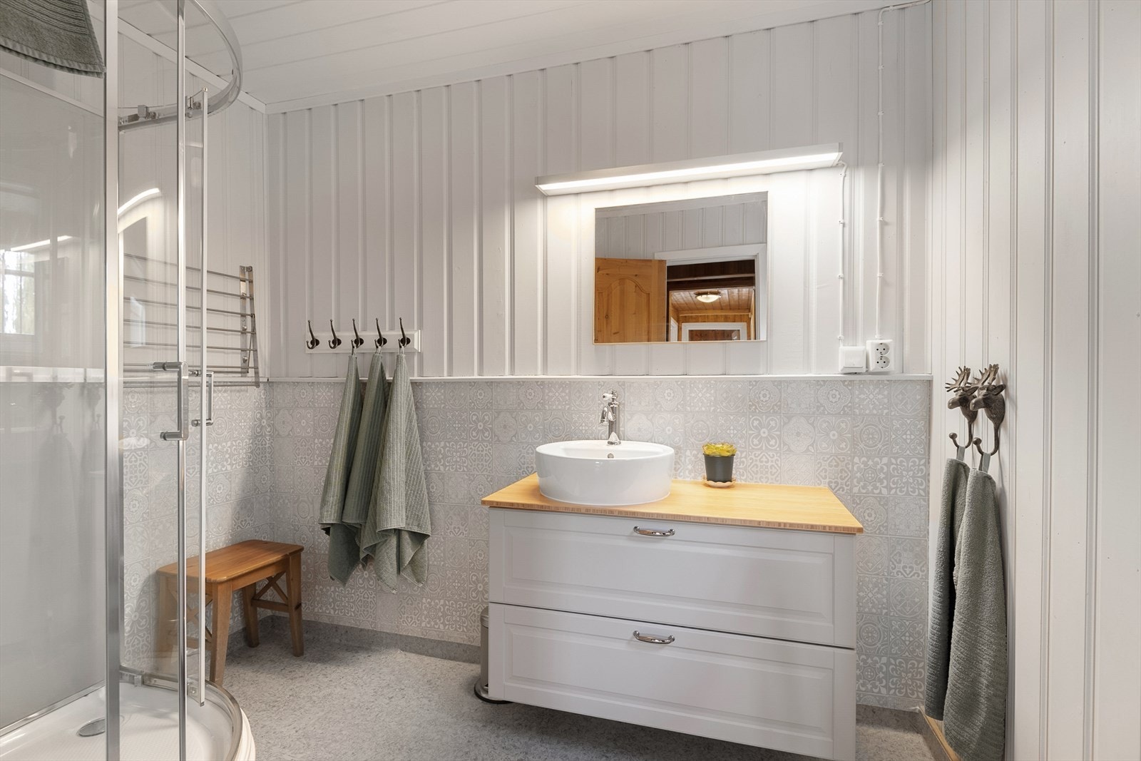 Lyst og delikat baderom med dusj og servantinnredning. Galleribilde