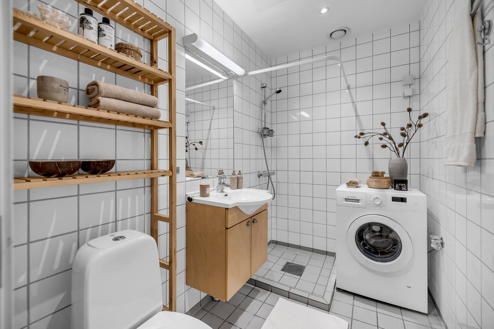 Lyst bad med flislagt gulv med gulvvarme og flislagte vegger, samt nedsenket himling med downlights. Galleribilde