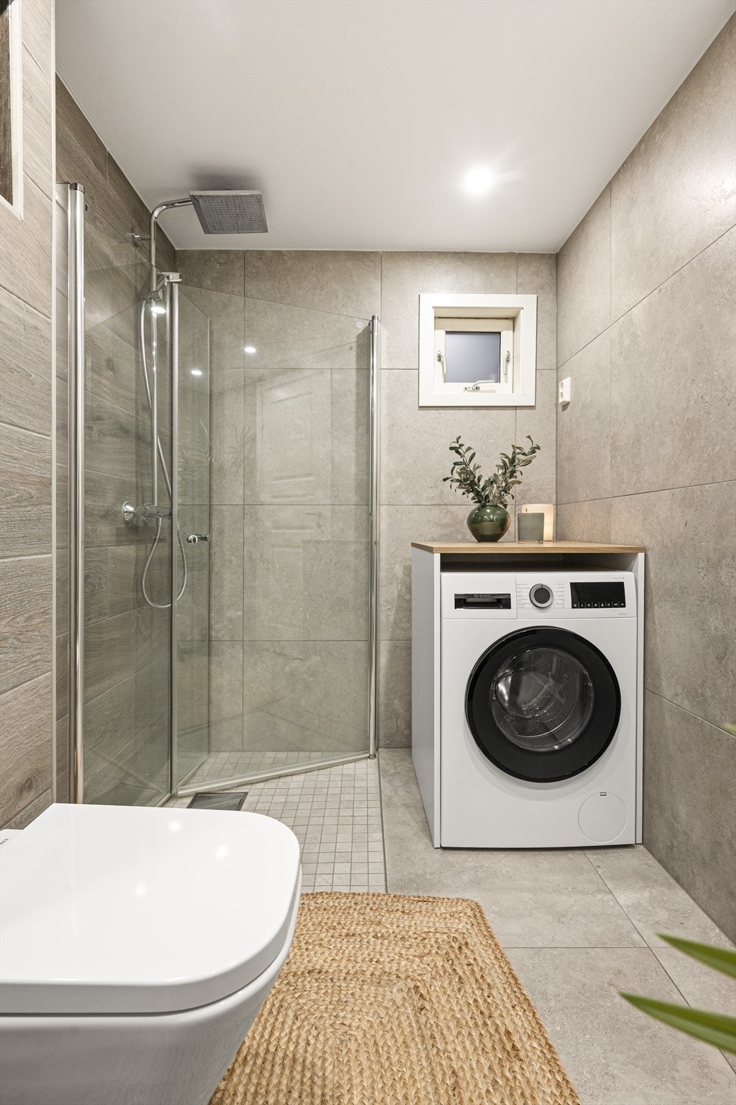 Videre er det dusjhjørne med glassdører i tillegg til opplegg for vaskemaskin. Galleribilde