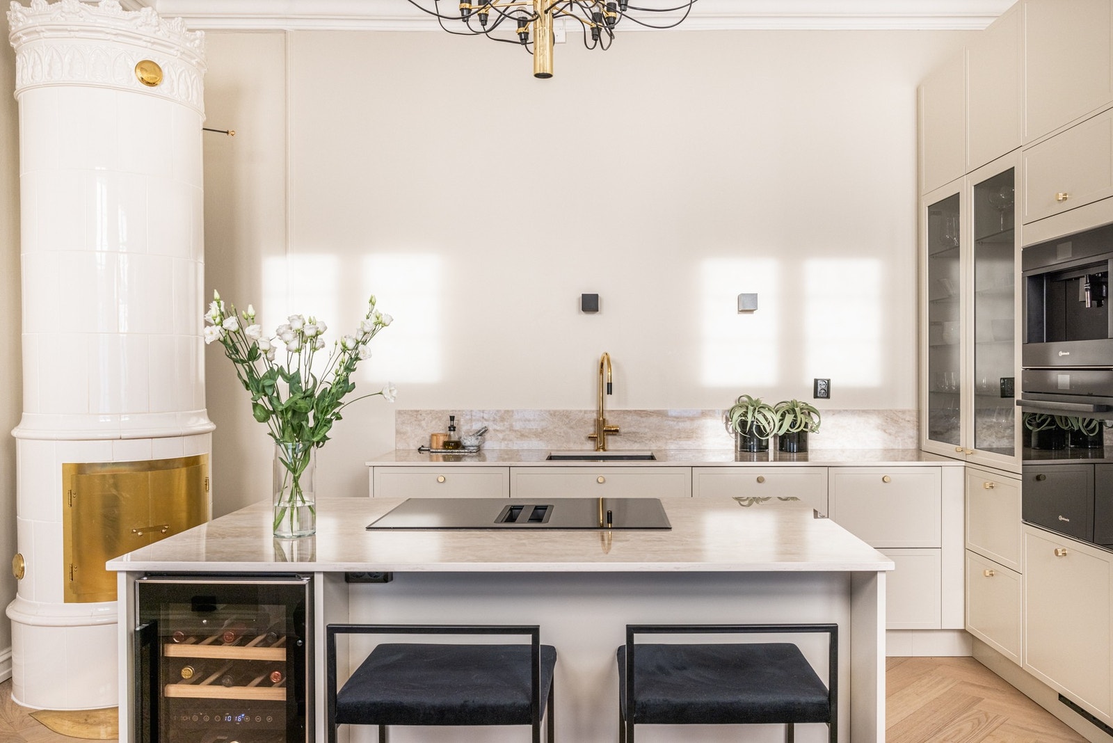 Lekkert kvalitetskjøkken fra norske Strai med steinkompositt benkeplater fra Dekton Arga og kjøkkenøy med integrert induksjonstopp fra Sliverline med innebygget ventilator. Vinskap. Galleribilde