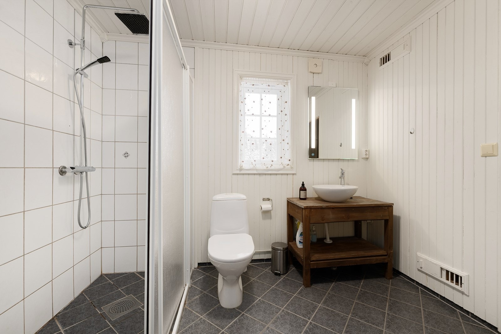 Badet i første etasje er flislagt og utstyrt med dusjhjørne og servant. Galleribilde